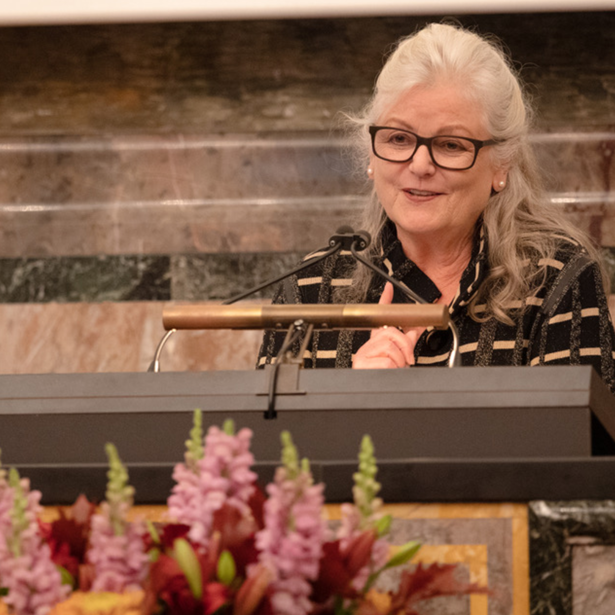 Ulrike Müller-Böker spricht in der Aula der UZH von der Kanzel, vor der Kanzel steht ein Blumenstrauss