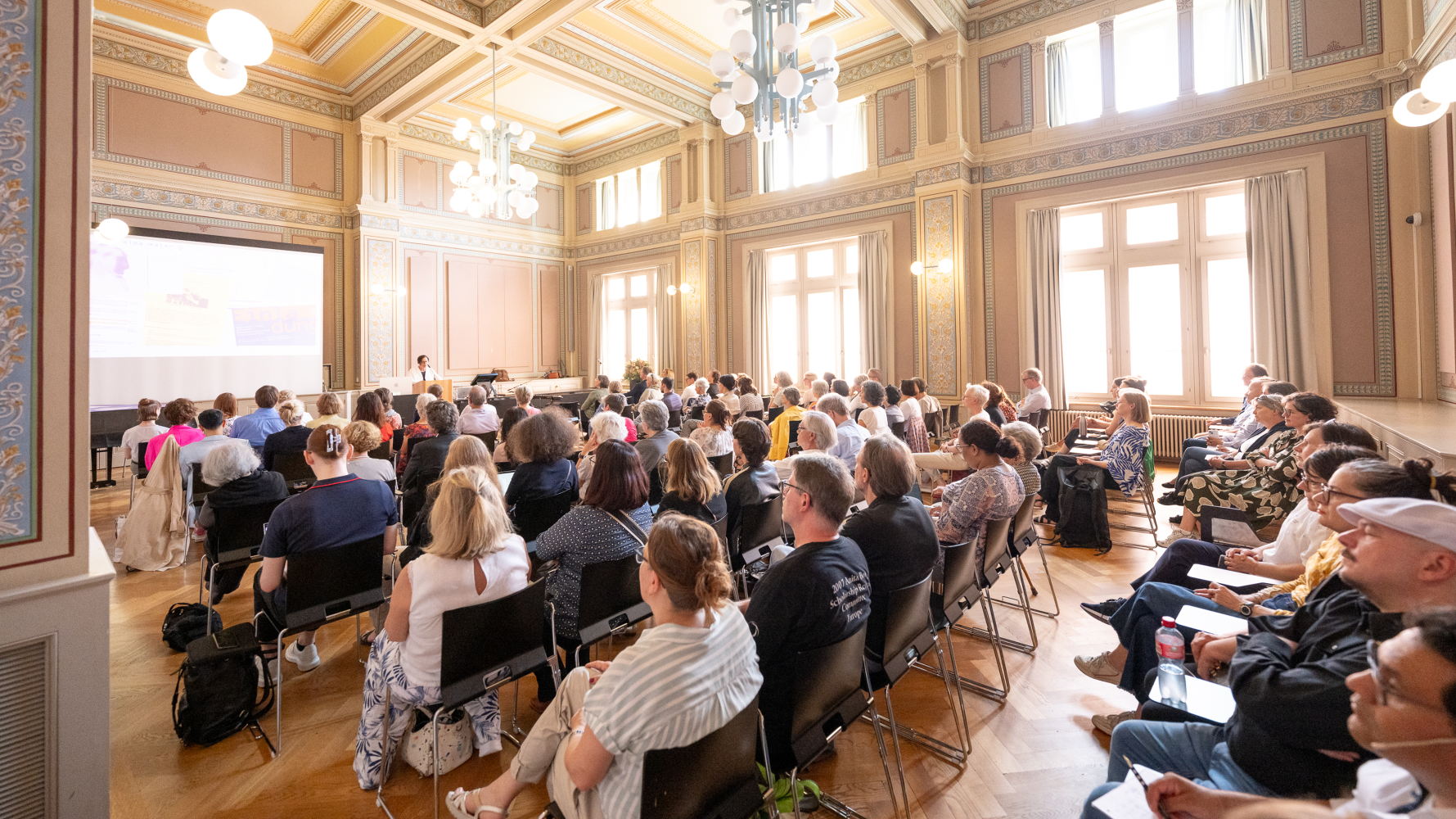 Im Raum RAA-G-01 in der Rämistrasse 59 sitzen die Gäste der Veranstaltung und lauschen der Begrüssungsrede von Vizerektorin Gabriele Siegert. Foto: Frank Brüderli